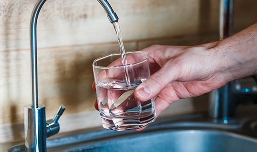 hand holding a glass of water. a man pouring water from filter tap.